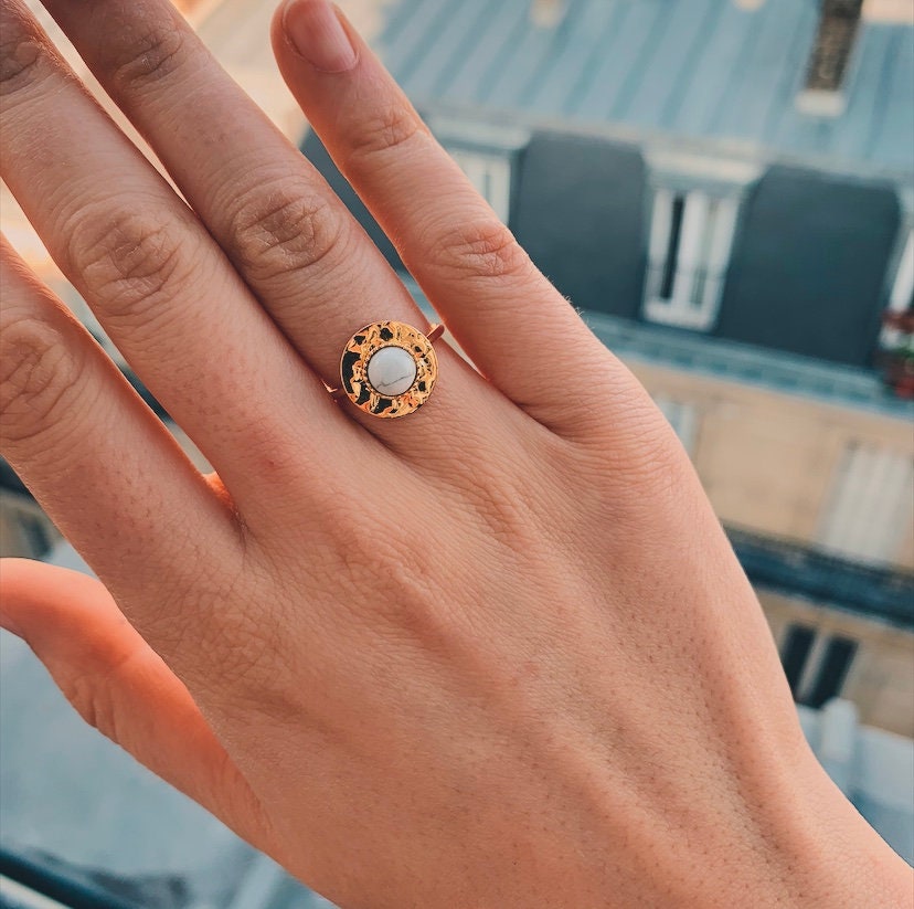 Peut inclure: Une bague en or avec une pierre blanche sertie dans un cadre circulaire texturé.
